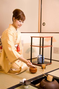 Japon geleneksel giysileri içinde çay yapan genç Asyalı kadın.