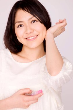 Arka planda sprey şişesi olan güzel bir Asyalı kadın.