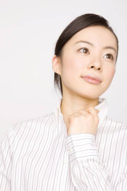 Genç Asyalı iş kadını beyaz arka planda soyutlanmış bir şekilde başka tarafa bakıyor. 