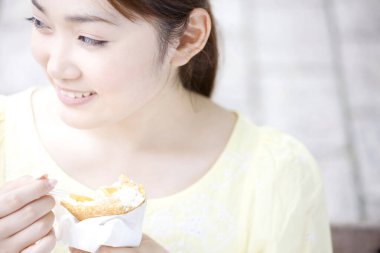 Genç Asyalı kadın dışarıda dondurma yiyor. 