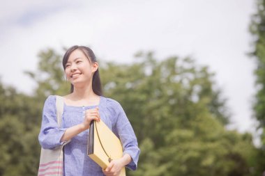 Neşeli Japon kadın gündüz vakti yeşil yaz parkında yürüyor. 