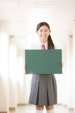 Elinde boş yeşil tahta tutan güzel Japon okul kızının portresi.