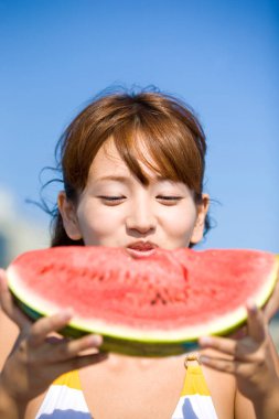 Elinde karpuz dilimiyle bikinili bir kadın. 