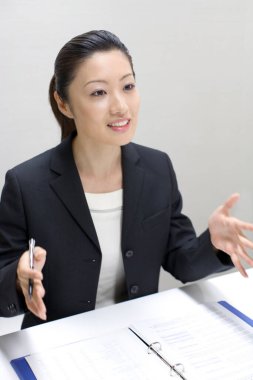 İş kadını ofiste dosyasının açık olduğu masada oturuyor.