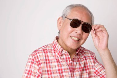 Stüdyoda güneş gözlüğü takan kıdemli Asyalı adam.