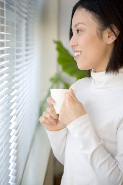 Genç bayan evde kahve içiyor. 