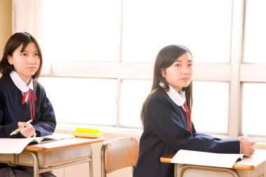 Genç Asyalı liseli kızlar modern sınıfta okuyor.