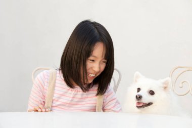 Şirin, mutlu Japon kızın yavru köpeğiyle portresi.