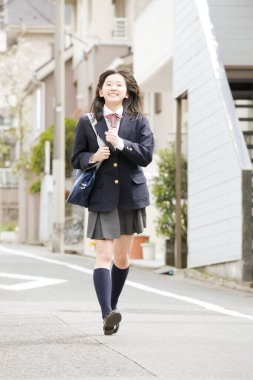 Sokakta koşan üniformalı güzel Japon kız.