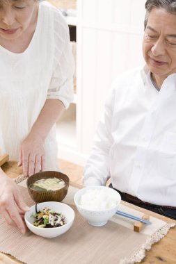 Kocasıyla yemek yiyen Asyalı kadının portresi.