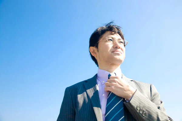 青空の背景に対する若いアジアのビジネスマンの肖像画 — ストック写真