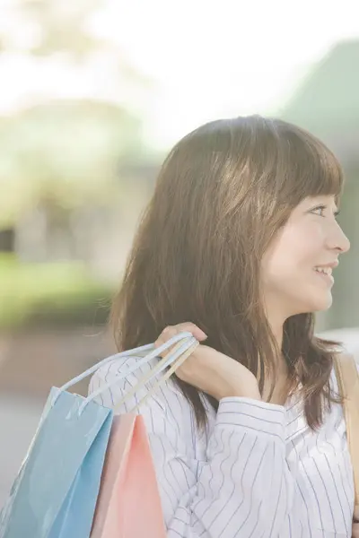 在城市里拿着购物袋的美丽而快乐的年轻亚洲女人 — 图库照片