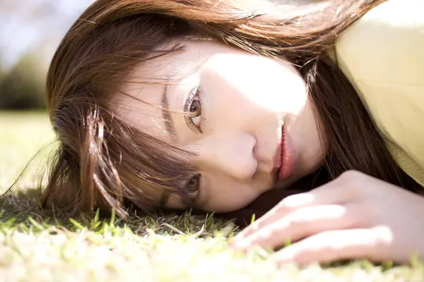 草の上に横たわり 公園でカメラを見ている魅力的なアジアの若い女性 — ストック写真