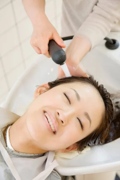 Young Japanese woman doing hairdressing in salon. Beauty Japanese lady making stylish haircut
