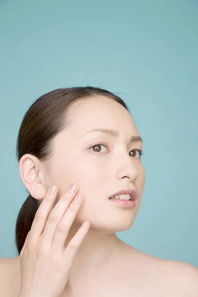 Junge Asiatische Frau Berührt Ihr Gesicht Isoliert Auf Blauem Hintergrund — Stockfoto