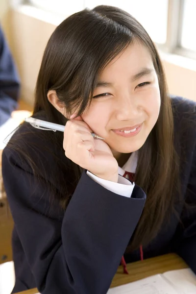 女子生徒が学校の机に座っている スクールユニフォームの美少女の肖像画 — ストック写真