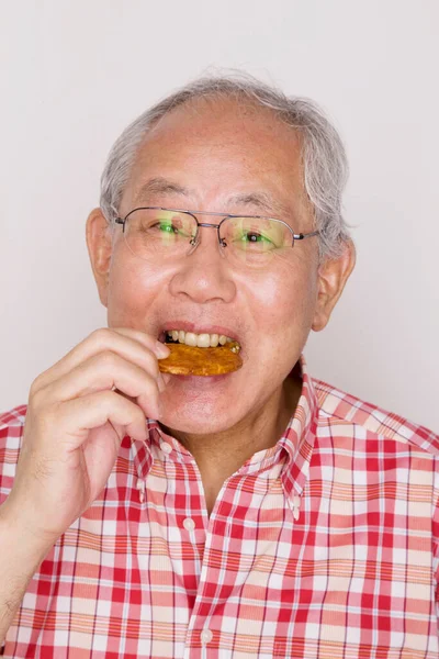 クッキーを食べるシニアアジアの男 — ストック写真