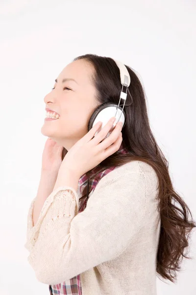 美丽而快乐的年轻女子的肖像 她用白色背景的耳机听音乐 — 图库照片