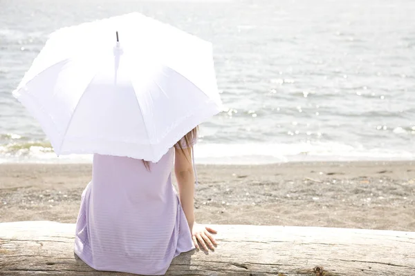 海岸に傘を差した若い女性が — ストック写真