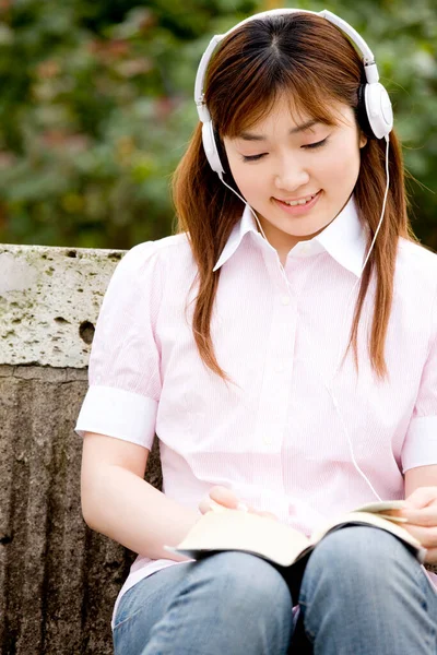 Genç Japon Kadın Kitapla Kulaklıkla Müzik Dinliyor — Stok fotoğraf