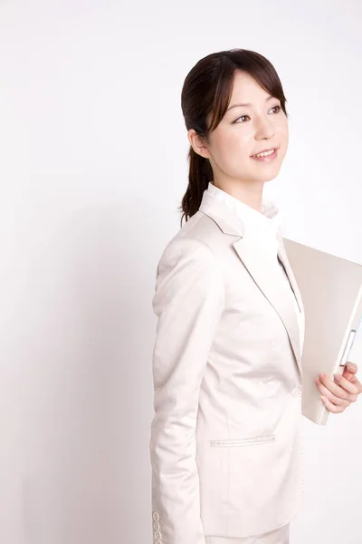 穿着西服的年轻日本女商人拿着文件夹 把目光投向了灰色背景 — 图库照片