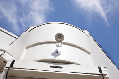 Mavi gökyüzü beyaz çatılı modern bir bina.