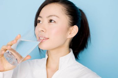 Güzel, genç Asyalı kadın izole edilmiş arka planda su içiyor.