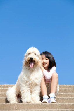 Şirin, mutlu Japon kızın yavru köpeğiyle portresi.