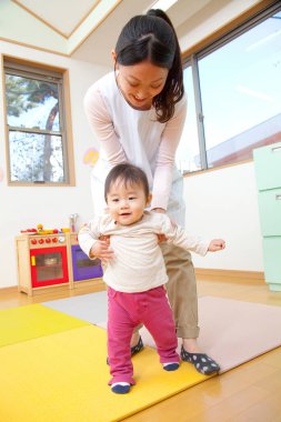 Küçük tatlı çocuk Japon anaokulunda öğretmenle oynuyor.