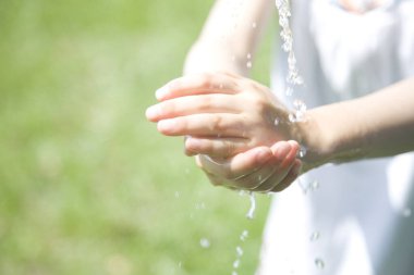 Küçük kız dışarıda suyla ellerini yıkıyor.