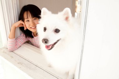 Şirin, mutlu Japon kızın yavru köpeğiyle portresi.