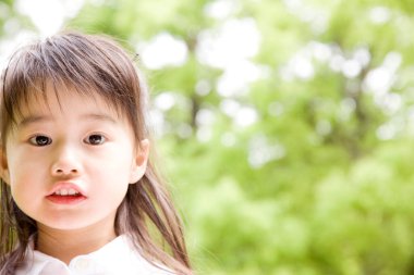 Yaz parkında gülümseyen küçük Asyalı kız.