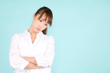Güzel genç Asyalı üzgün kadın mavi arka planda izole edilmiş.