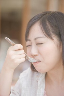 Kafede tatlı yiyen mutlu Asyalı genç kadın.