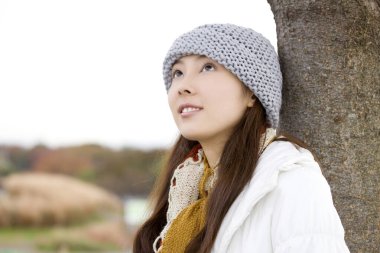 Kış eşarbı ve şapka takan Asyalı genç kadının portresi.