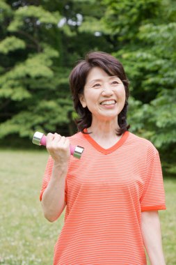 Olgun Asyalı kadın halterle egzersiz yapıyor.