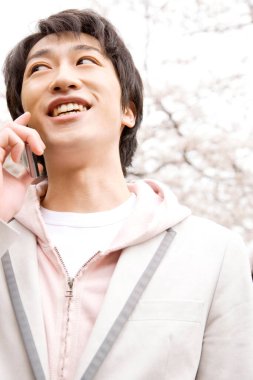 Baharda Sakura çiçeği açarken parkta telefonla konuşan genç Japon işadamının portresi.