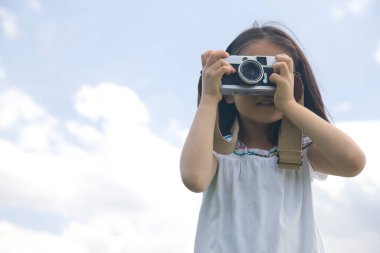 Küçük Asyalı kız dışarıda fotoğraf makinesi kullanıyor.