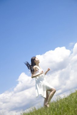 Yeşil çimlerde koşan güzel genç bir Japon kadın.