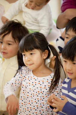 Bir grup Asyalı küçük çocuk Japon anaokulunda gülümsüyor.