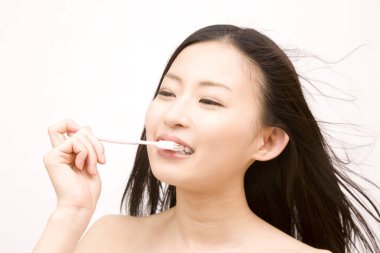 Asyalı kadın diş fırçasıyla dişlerini fırçalıyor