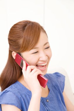 Evde cep telefonu kullanan Asyalı kadın. 