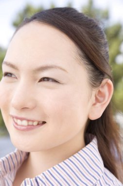 Dışarıda gülümseyen Asyalı genç bir kadın portresi.