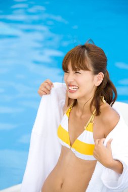 Yüzme havuzunun yanında beyaz bornoz giyen güzel Asyalı genç bir kadın.
