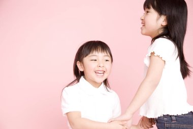 İki küçük Asyalı kız el ele tutuşuyorlar. 