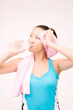 Spor sonrası su içen Asyalı genç bir kadın. 