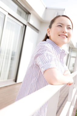 Genç bir kadın yatta dururken denize bakarak gülümsüyor.