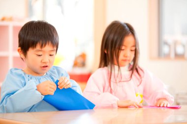 Japon anaokulunda kağıt origami yapan iki şirin Asyalı çocuk.