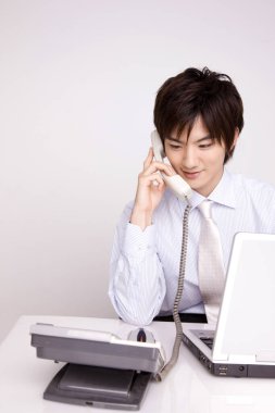 Genç Asyalı işadamı telefonda konuşuyor. 