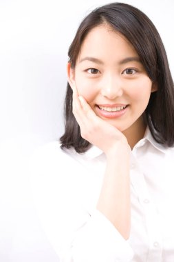 Genç, güzel Asyalı kadın beyaz arka planda yalnız poz veriyor.